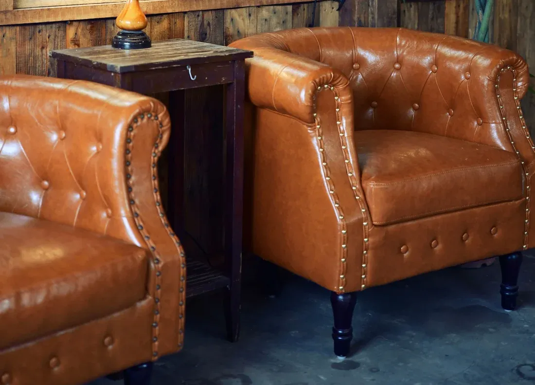 Two tan buttoned leather club chairs