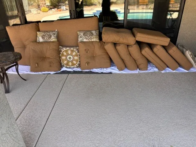 Patio furniture cushions laid out on a pool deck ready for cleaning